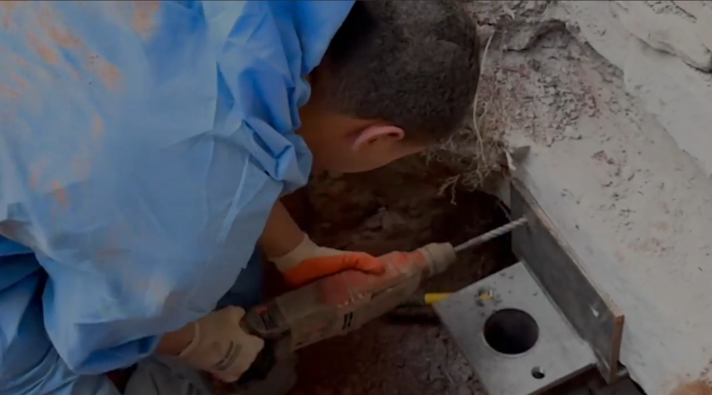 Worker installing push pier to level foundation